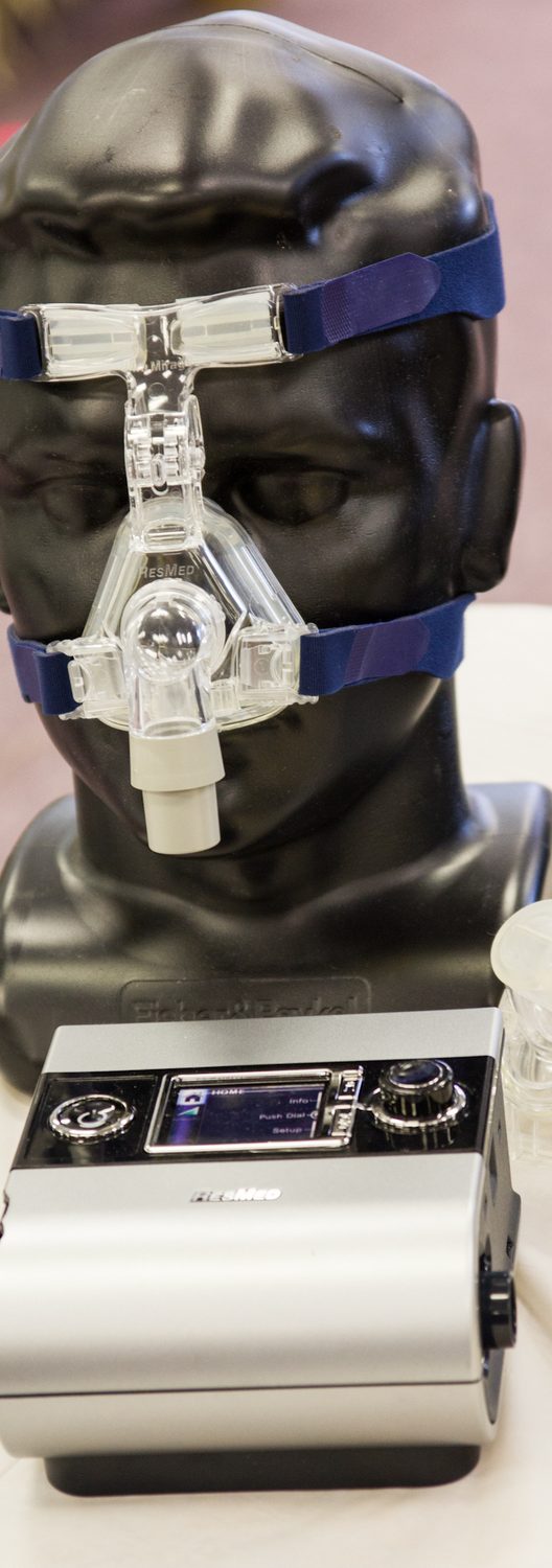 A CPAP nasal mask on a model head, with a CPAP machine in front